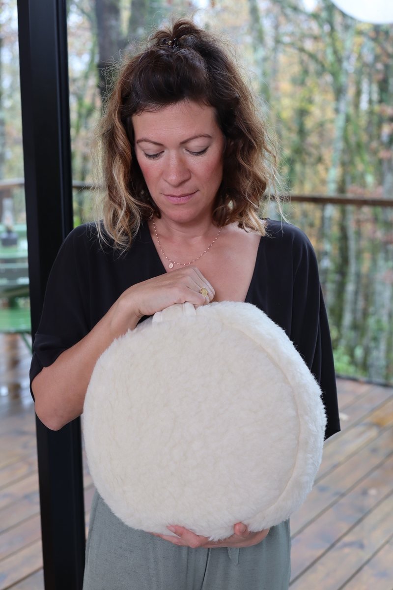Femme tenant contre elle un coussin de méditation rond en laine mérinos
